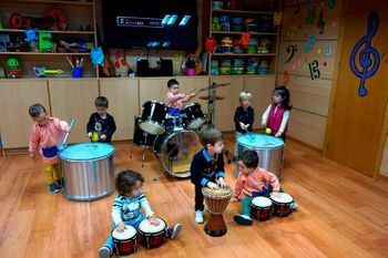 Un grupo de niños está tocando la batería en una habitación.