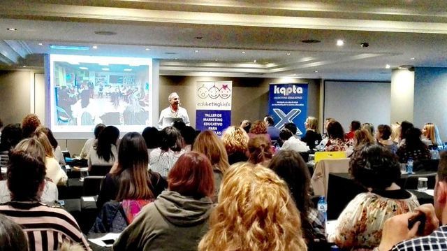 Un grupo grande de personas está sentado en una sala de conferencias viendo una presentación.