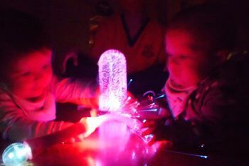 Dos niños están jugando con un objeto brillante en la oscuridad.