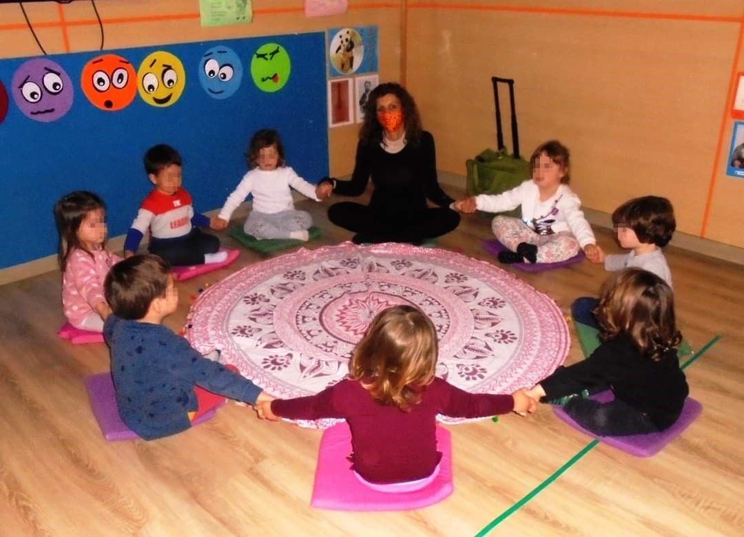 Un grupo de niños están sentados en círculo con los brazos extendidos.