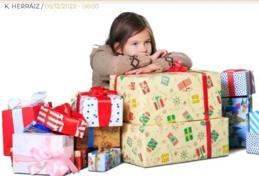 Una niña apoyada en una pila de regalos de Navidad.