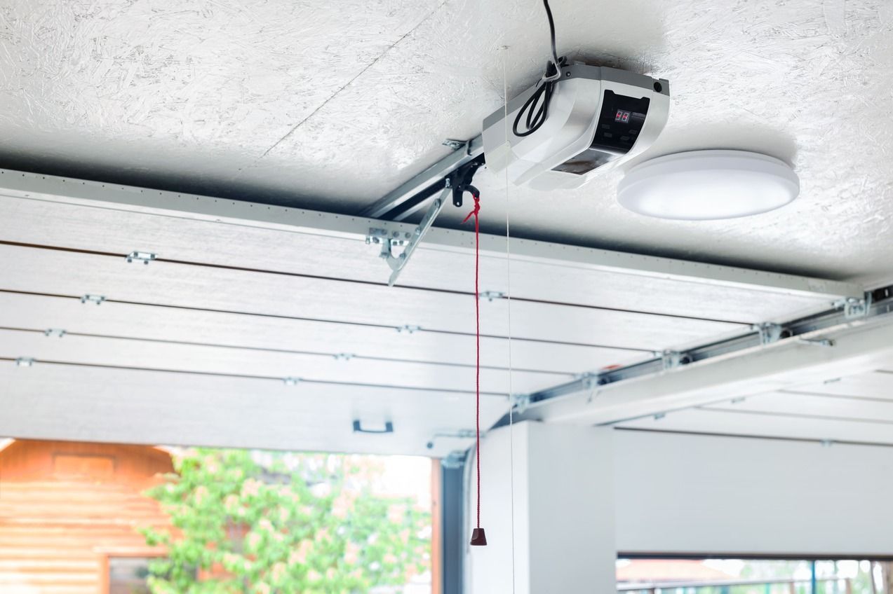 Abre-puertas de garaje fijado al techo con cable de emergencia rojo.