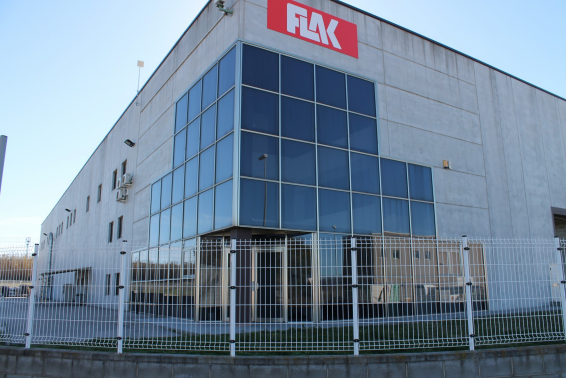 Un edificio industrial gris con ventanas de vidrio y el logotipo 