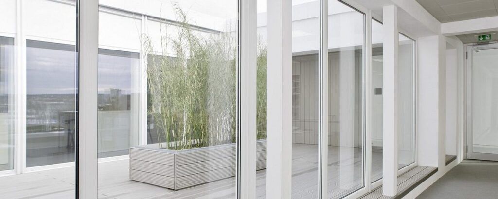 Interior moderno con grandes ventanales que dan a una terraza con plantas.