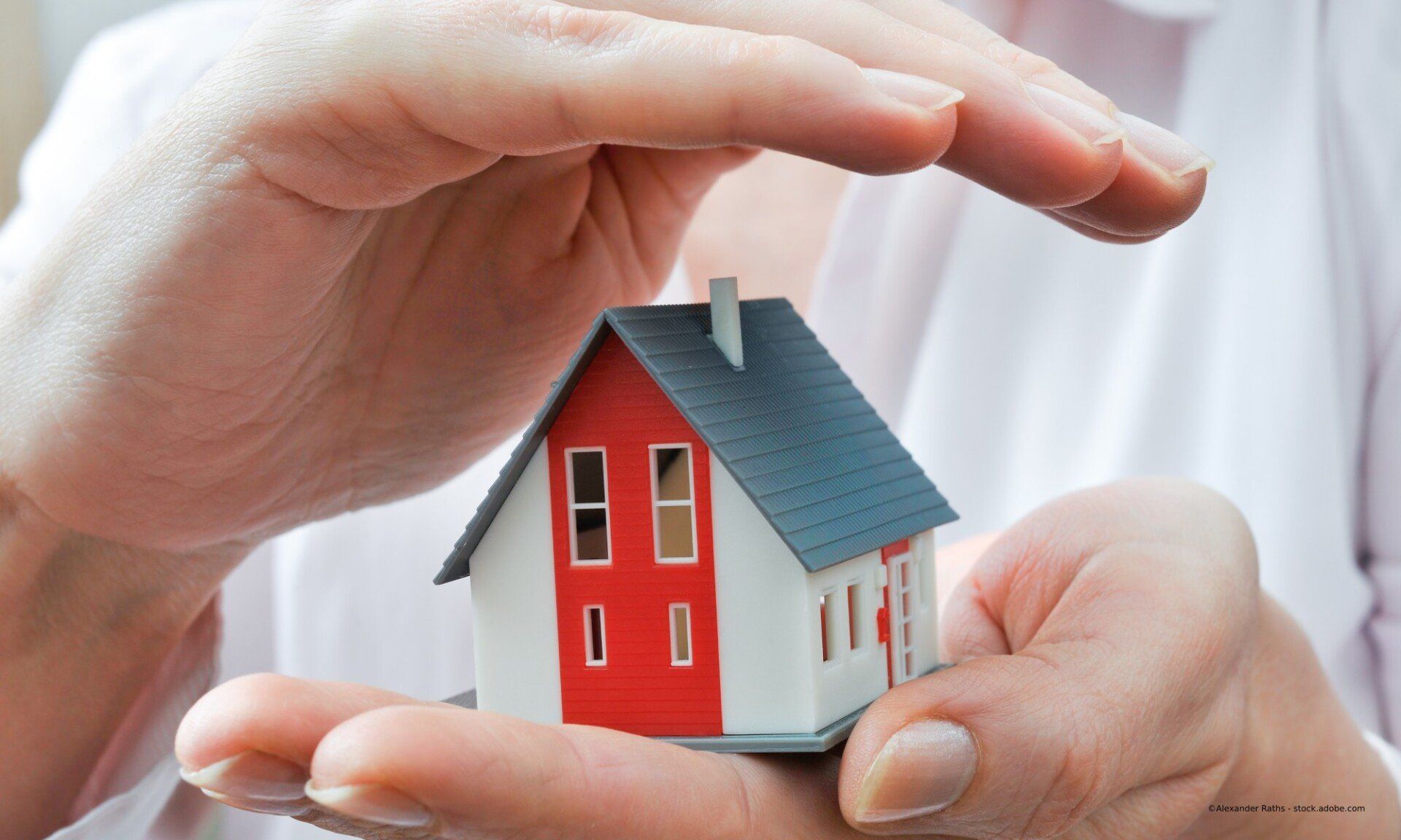 Mitarbeiter von BuC Immobilien Management Brenner Daniel erklärt etwas, Modellhaus auf dem Schreibtisch