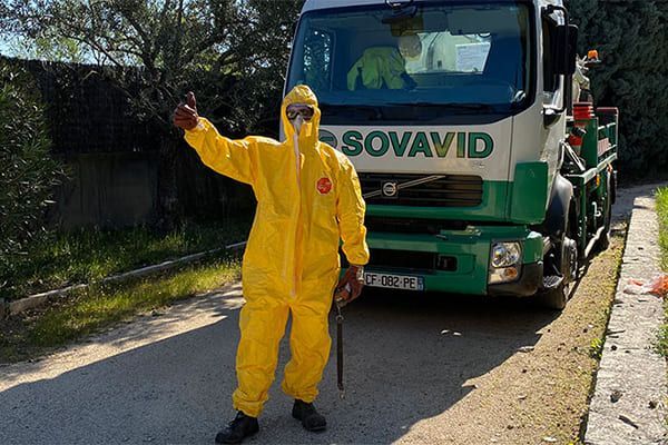 Homme en combinaison jaune devant un camion hydrocureur.