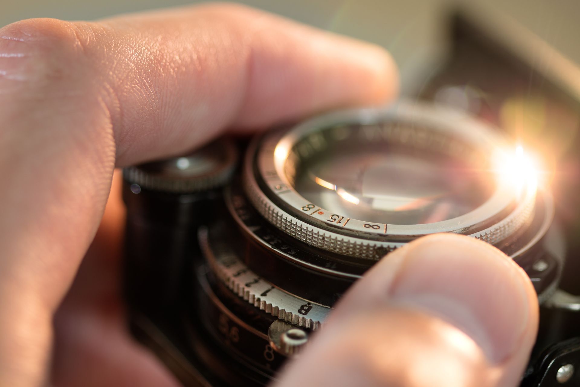 Une main d'homme règle l'objectif d'un appareil photo.