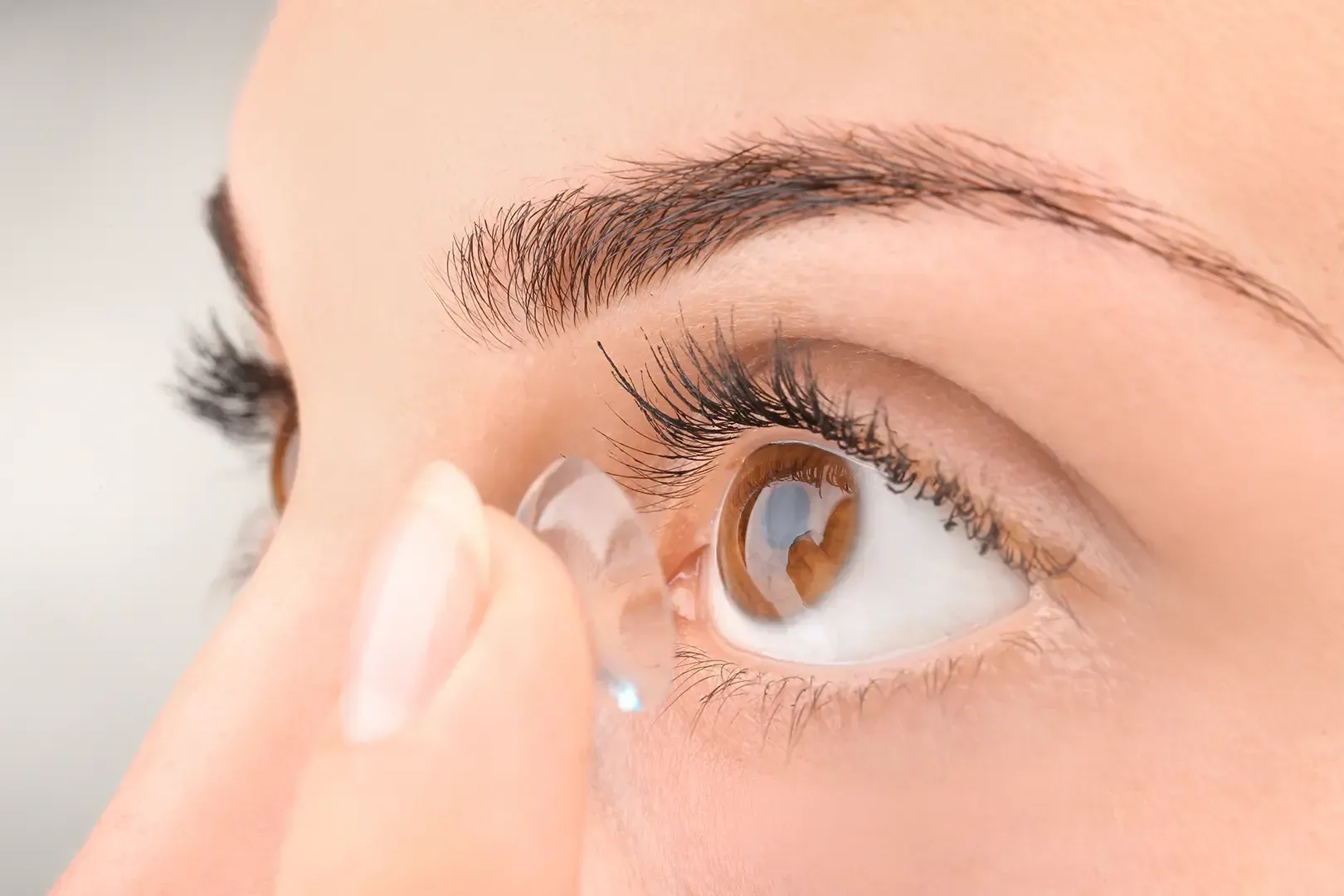Eine Person, die sich eine Kontaktlinse ins Auge einsetzt (Nahaufnahme)