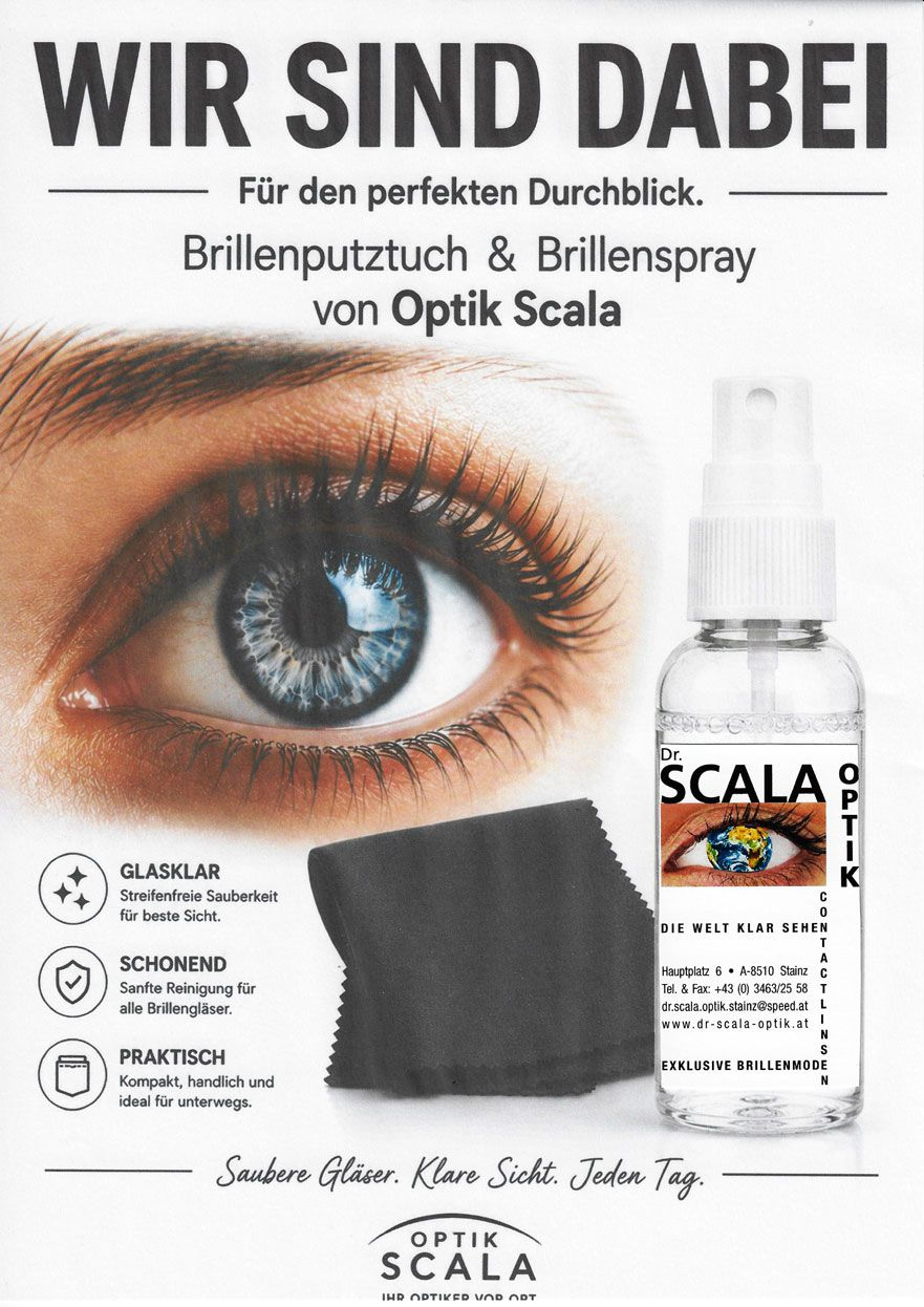 In einem Optikergeschäft steht eine Person mit verschränkten Armen; im verschwommenen Hintergrund arbeitet ein Kollege an einem Computer.