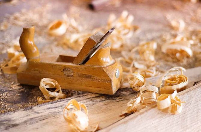 Holzhandhobel mit Spänen auf einer Holzoberfläche.
