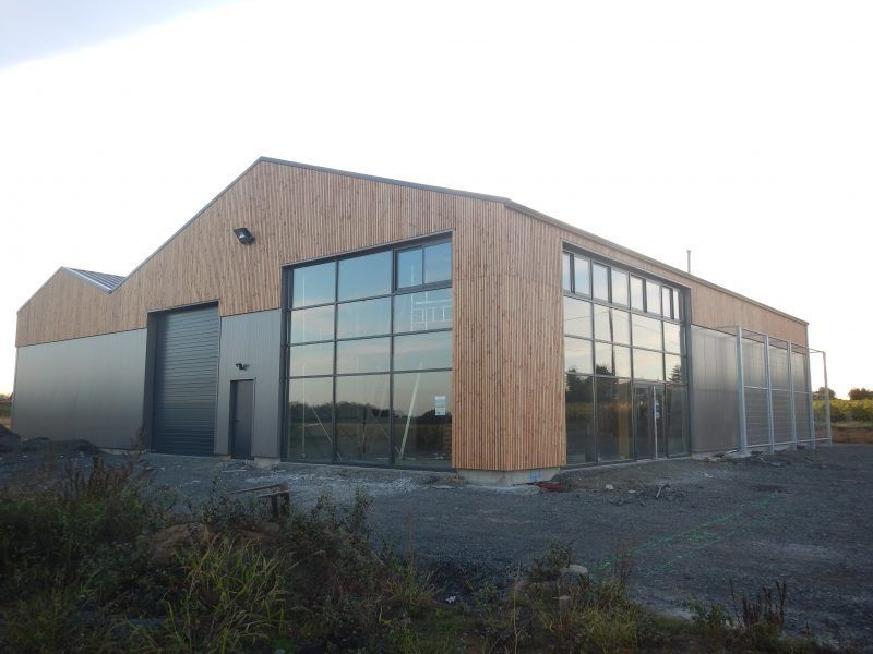 Bâtiment industriel moderne avec bardage en bois clair et grandes baies vitrées.