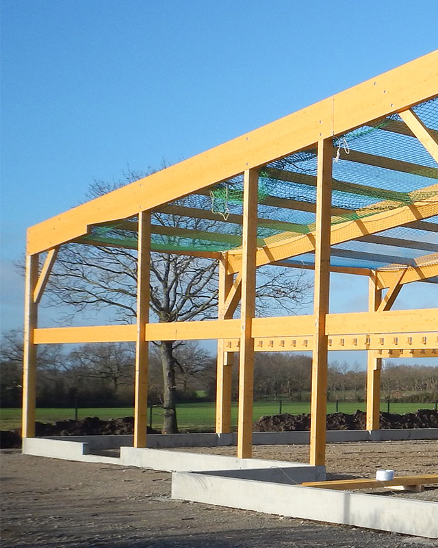 Structure à ossature bois en construction sur fondations en béton, ciel bleu dégagé.