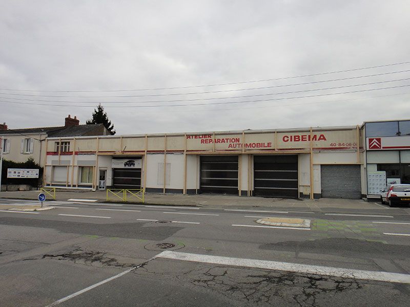 Vue extérieure d'un garage automobile fermé par temps nuageux, avec un passage piéton devant.