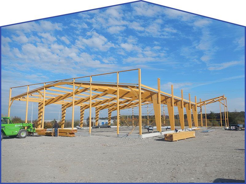 Bâtiment en bois en construction sur fond de ciel bleu, sol de gravier.