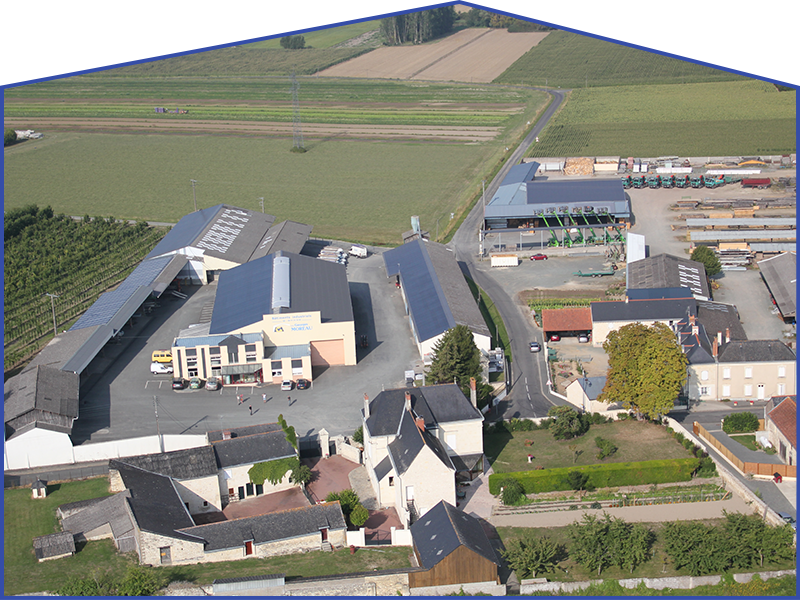 Vue aérienne de bâtiments, de champs verdoyants et d'une route.