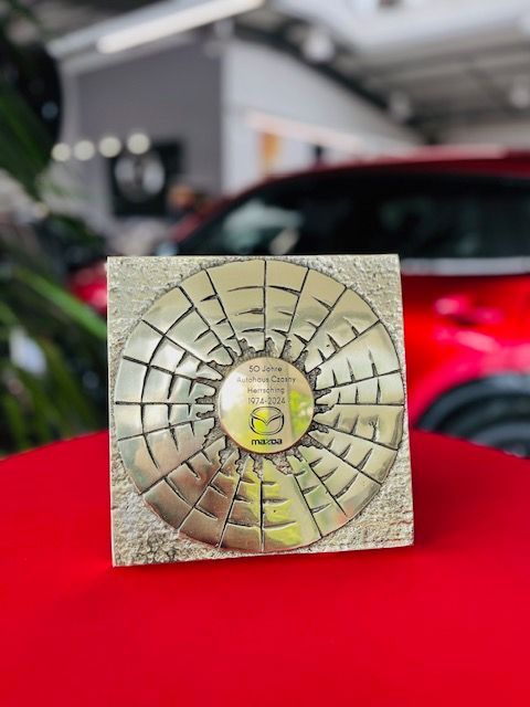 Auszeichnung auf einem roten Tuch im Hintergrund ein rotes Auto