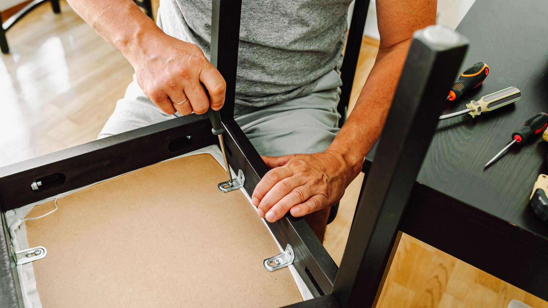 Une personne utilise un tournevis pour fixer un pied métallique à la structure.