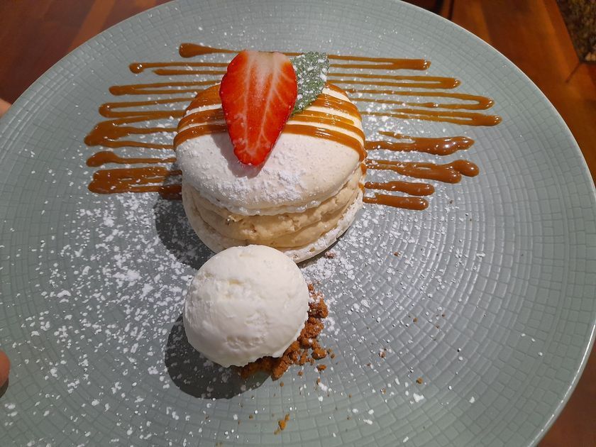 Assiette de dessert composée d'une pâte feuilletée, de fraises en garniture, de glace à la vanille et d'un filet de caramel.