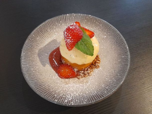 Dessert élégant aux fraises, feuilles de menthe et sauce, présenté sur une assiette en verre texturé.