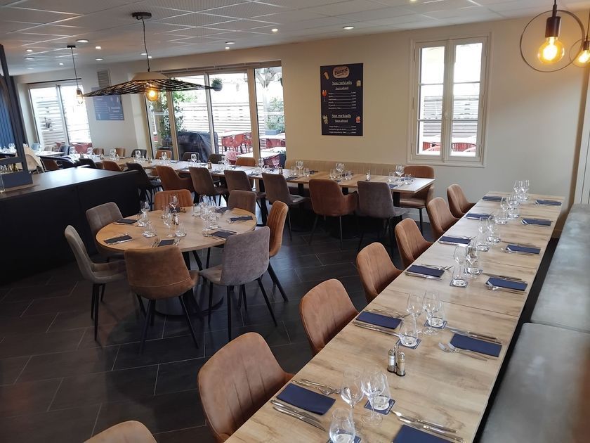 Salle à manger du restaurant vide, avec tables dressées et chaises beiges, vue de face.