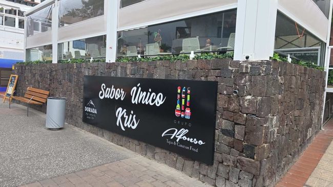 Exterior del restaurante con un cartel negro que dice 