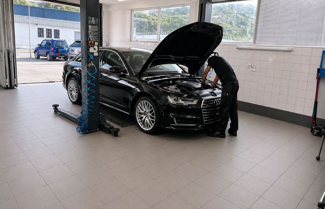 Voiture noire dans un garage, capot ouvert, pendant qu'un mécanicien inspecte le moteur.