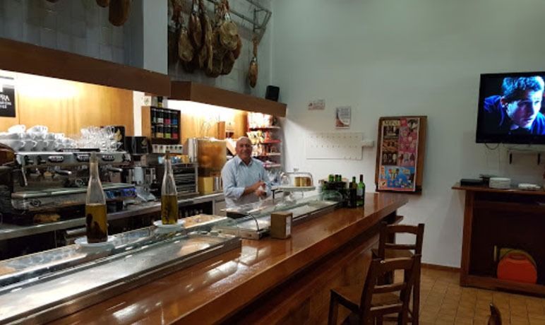 Un hombre se sienta en un bar frente a un televisor.