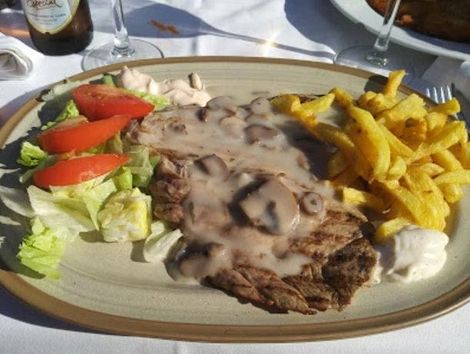 Un plato de comida con papas fritas y una ensalada en una mesa.