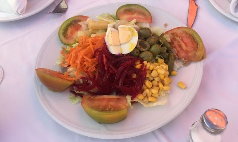 Un plato blanco cubierto con una ensalada de verduras y huevos.