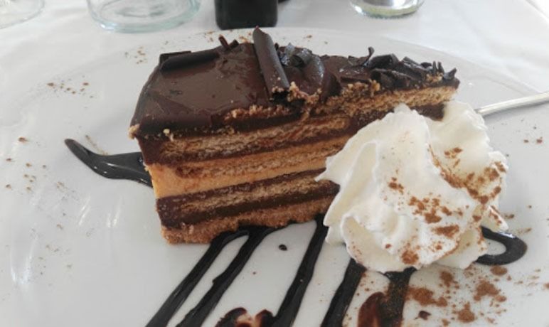 Una rebanada de pastel de chocolate con crema batida en un plato blanco.