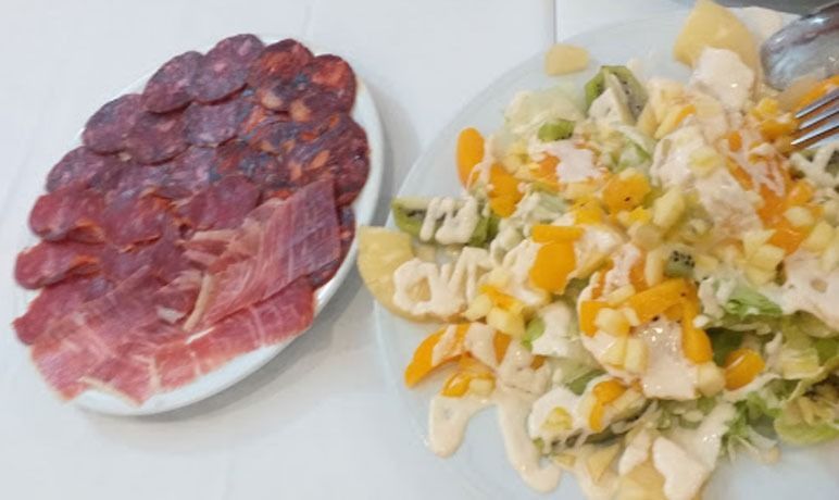 Un plato de carne y un plato de ensalada están sobre una mesa.