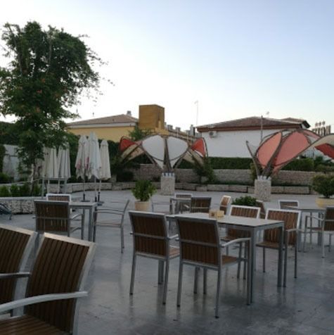 Un área de patio con mesas, sillas y sombrillas.