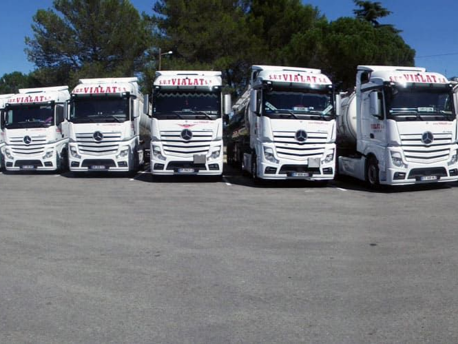 Une rangée de semi-remorques blancs garés sur un parking par une journée ensoleillée