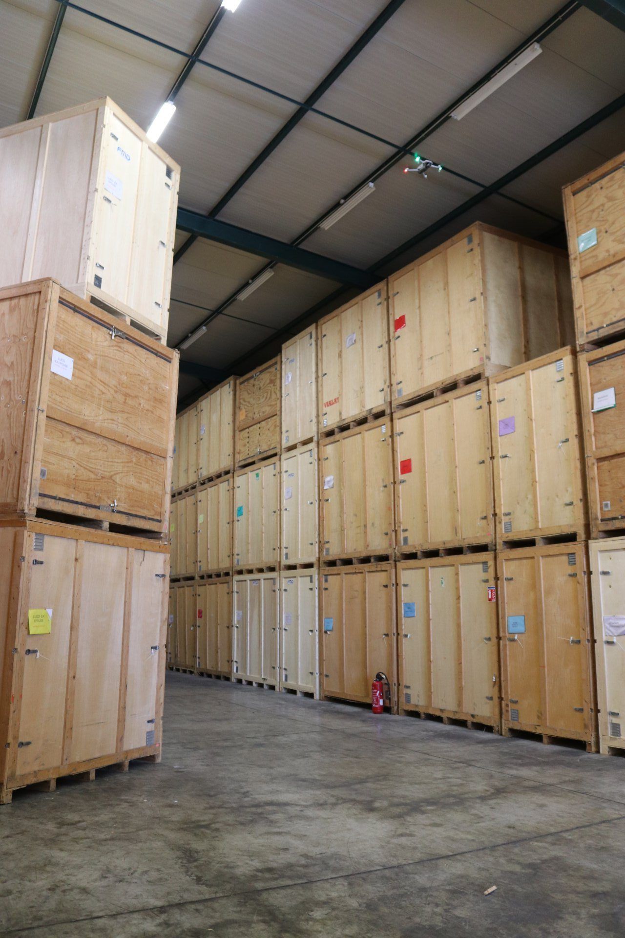 Des rangées de hautes caisses de stockage en bois dans une allée d'entrepôt au sol en béton et au plafond haut