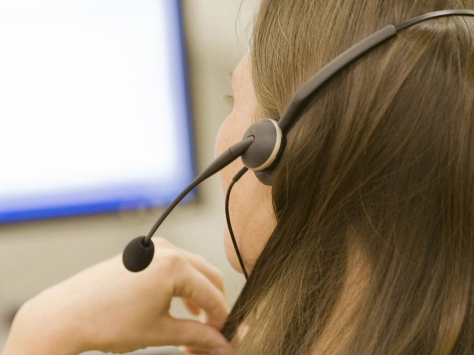 Une personne portant un casque-micro regarde un écran d'ordinateur