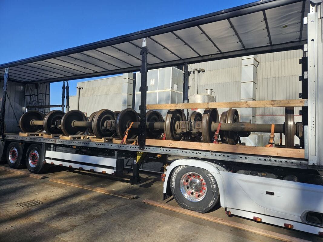 Semi-remorque à côtés ouverts transportant des rangées de grandes roues industrielles sur une zone de chargement
