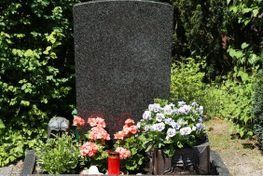 Una tumba con flores y una vela delante de ella.