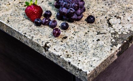 Una fresa, arándanos y uvas están sobre una encimera de granito.