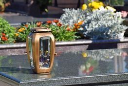 Una linterna está colocada encima de una tumba en un cementerio.