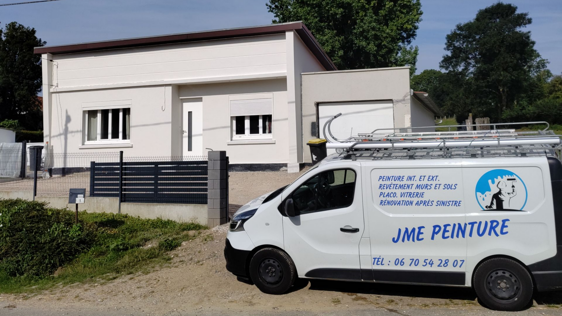 Une camionnette blanche est garée devant une maison moderne de plain-pied, de couleur claire.