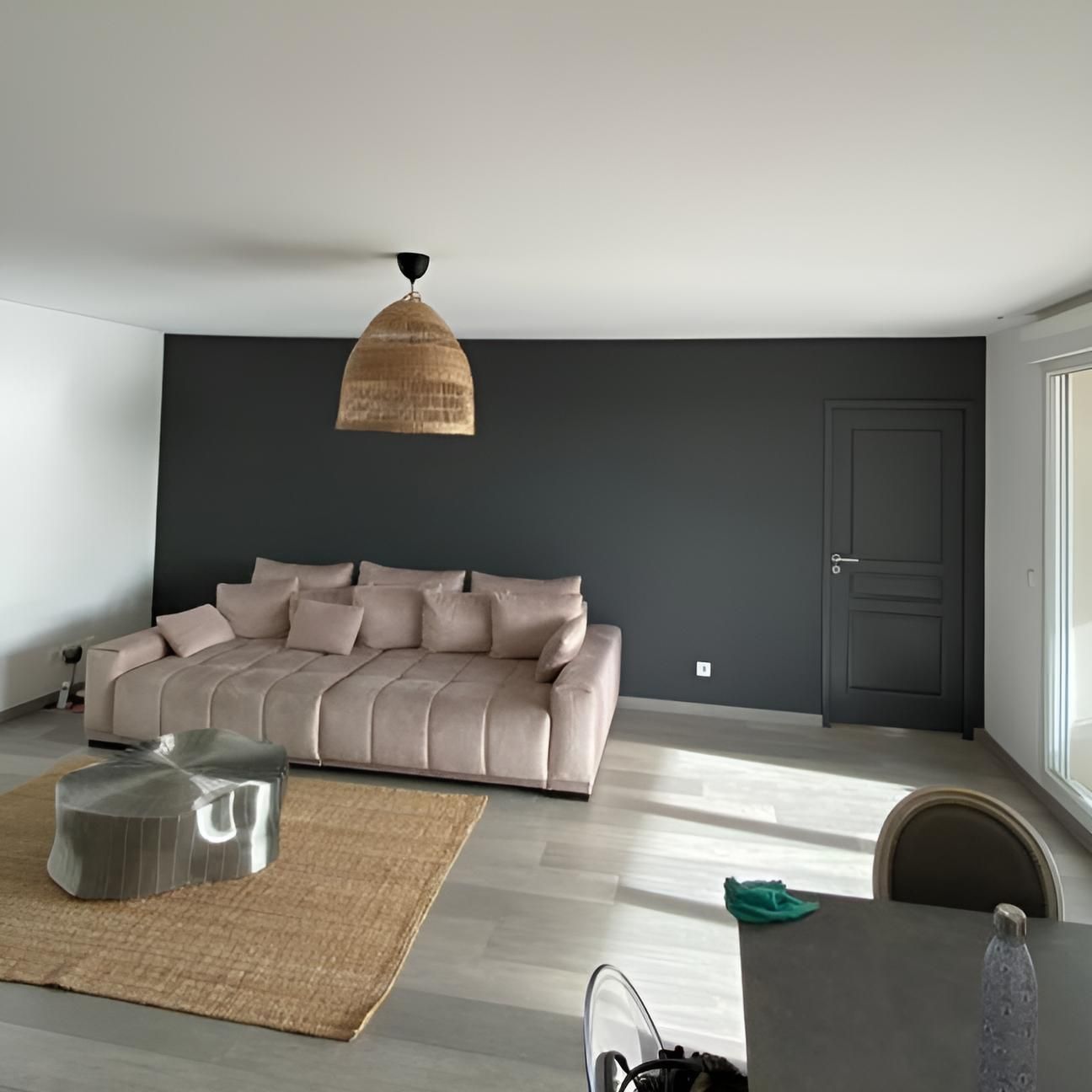 Salon moderne avec un mur d'accent marron, un canapé d'angle beige, un lampadaire et un coin repas en arrière-plan.