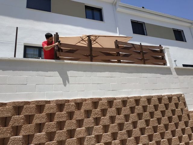 Un hombre está parado en un balcón sosteniendo un paraguas.