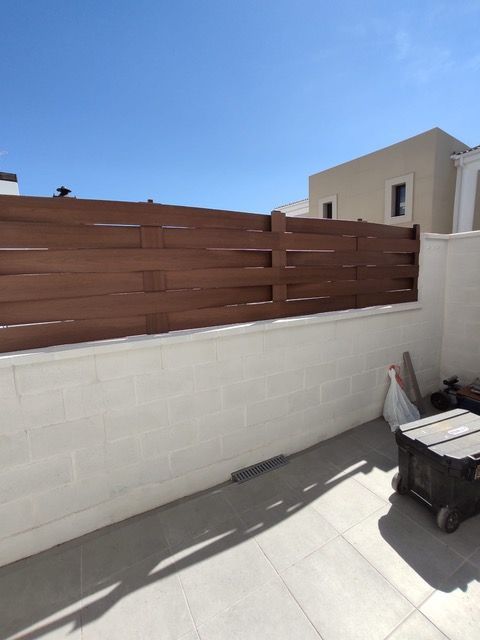 Una pared blanca con una valla de madera detrás.