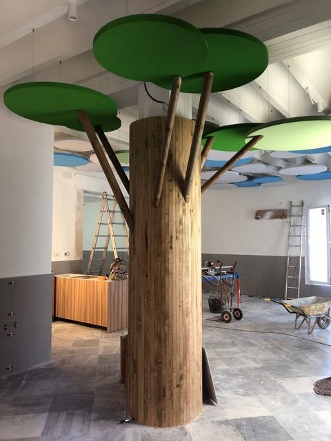 Un árbol de madera con hojas verdes está en una habitación.