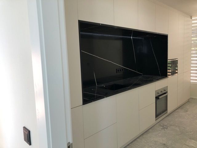 Una cocina con gabinetes blancos y encimeras negras.