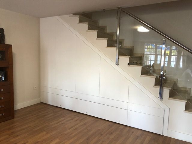 Una sala de estar con escaleras y barandilla de cristal.