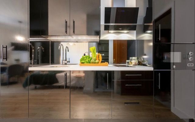 Una cocina con electrodomésticos de acero inoxidable y gabinetes negros.