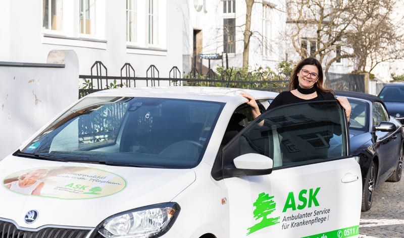 Eine Frau sitzt in einem Auto mit offener Tür.