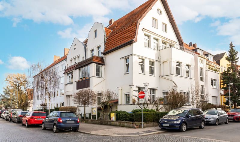 Ein großes weißes Gebäude mit davor geparkten Autos.