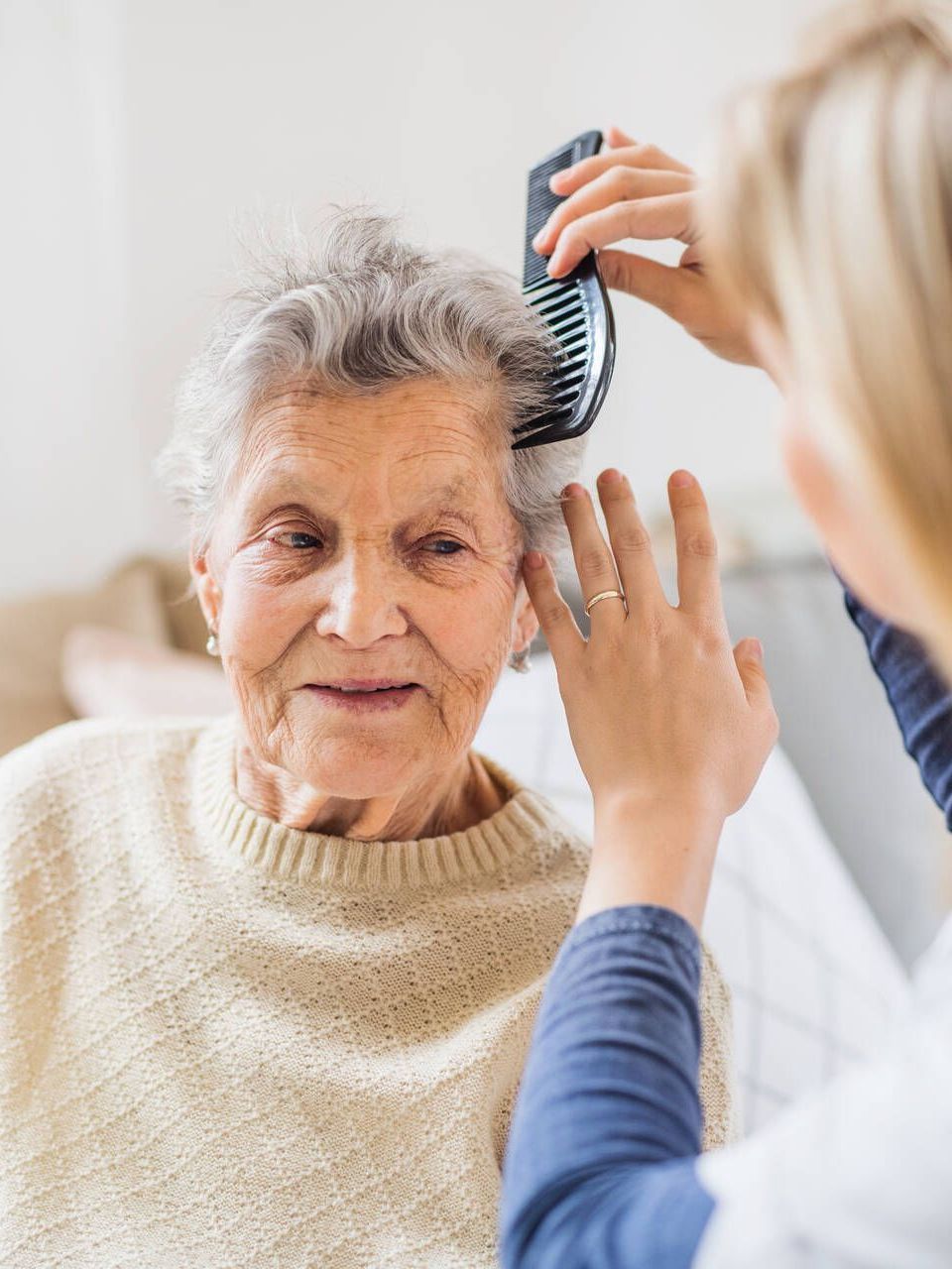 Eine Frau kämmt einer älteren Frau mit einem Kamm die Haare.